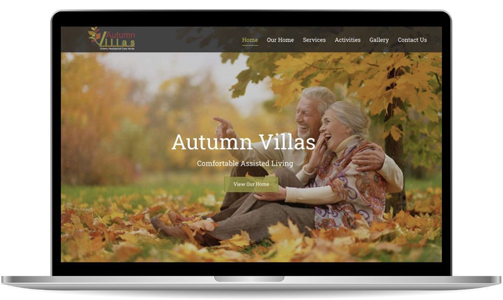 autum-villas Laptop screen displaying a webpage for Autumn Villas, showcasing an image of an elderly couple sitting on grass amid fall foliage. The website's menu and a button that reads "View Our Home" are visible.